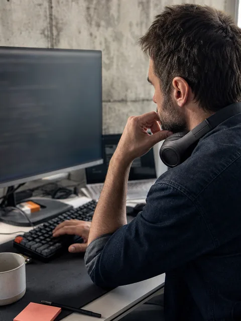 Backend developer writing Python at a desk with two monitors